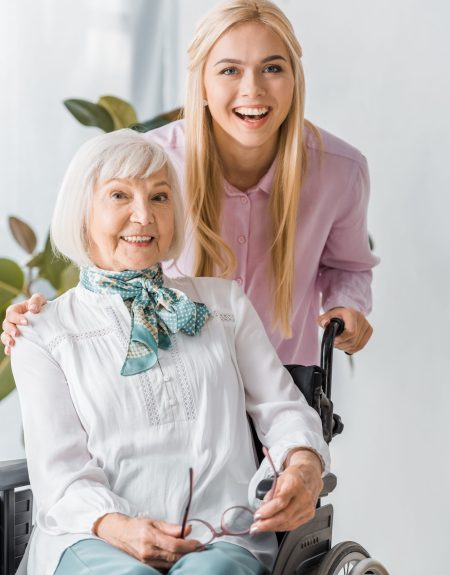 young and senior women in wheelchair smiling and looking at camera